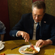 Ohio Gov. John Kasich pokes curiously at a slice of pizza with a fork. (Image via Getty)